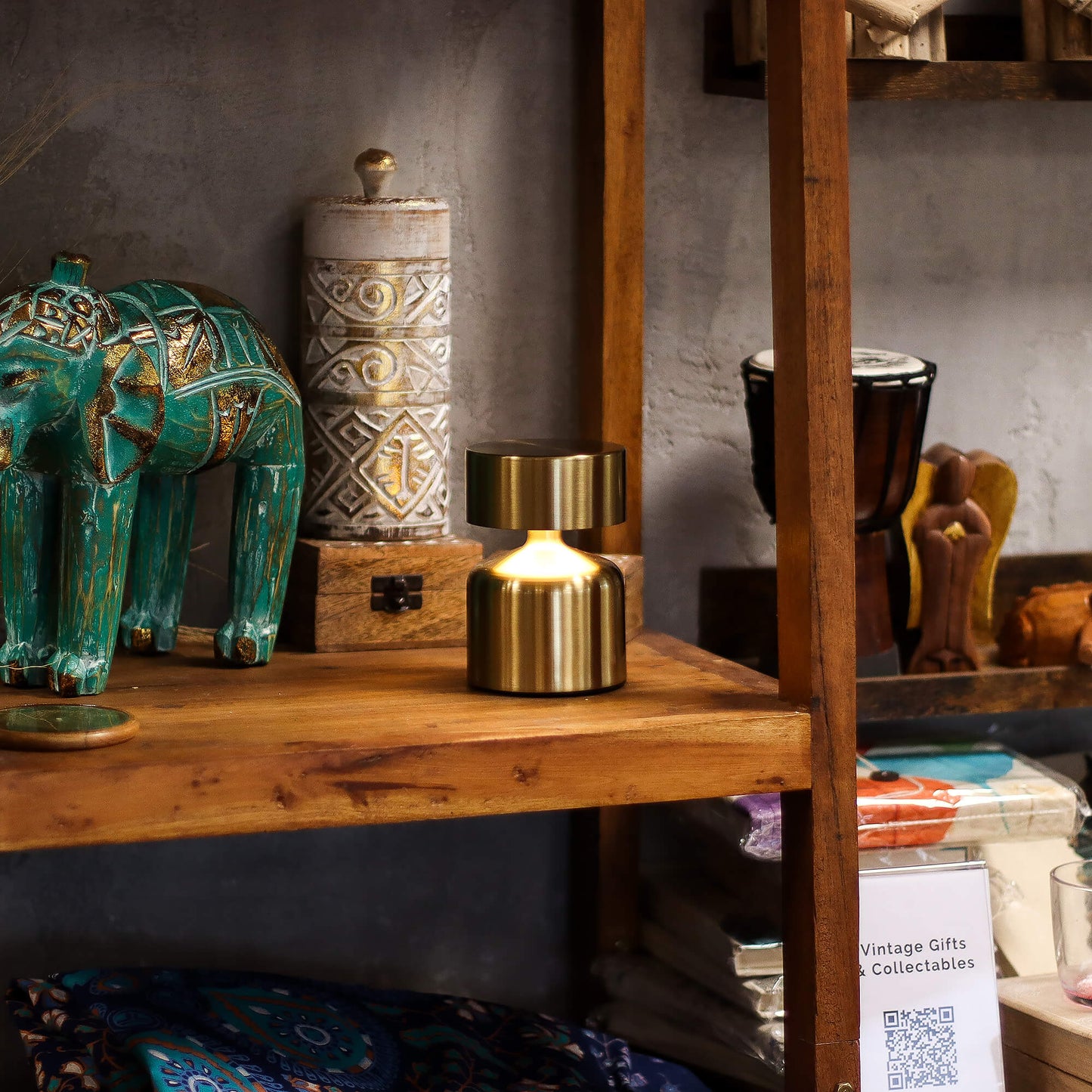 Bronze flat design touch lamp on a wooden shelf with a teal elephant and ceramic jars - Kraas