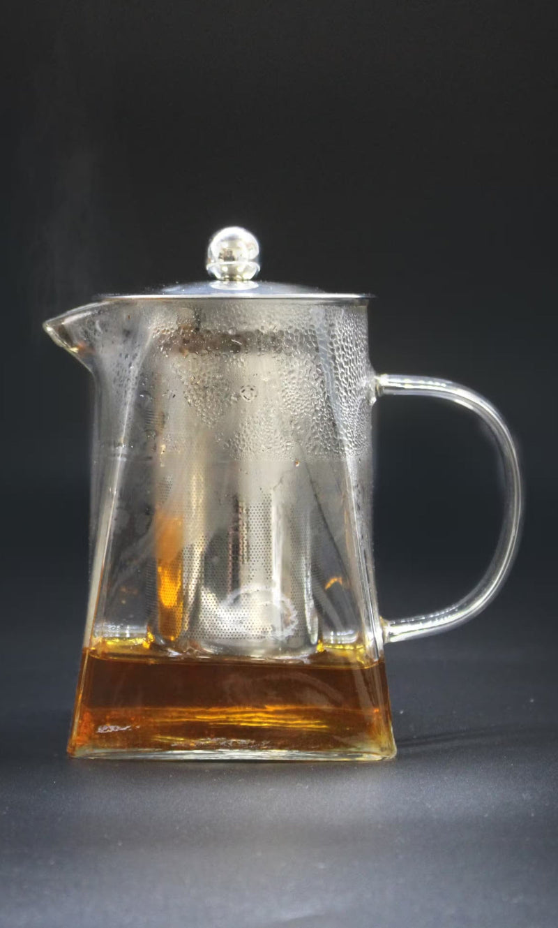Clear glass teapot with a silver lid and hot tea inside - Kraas
