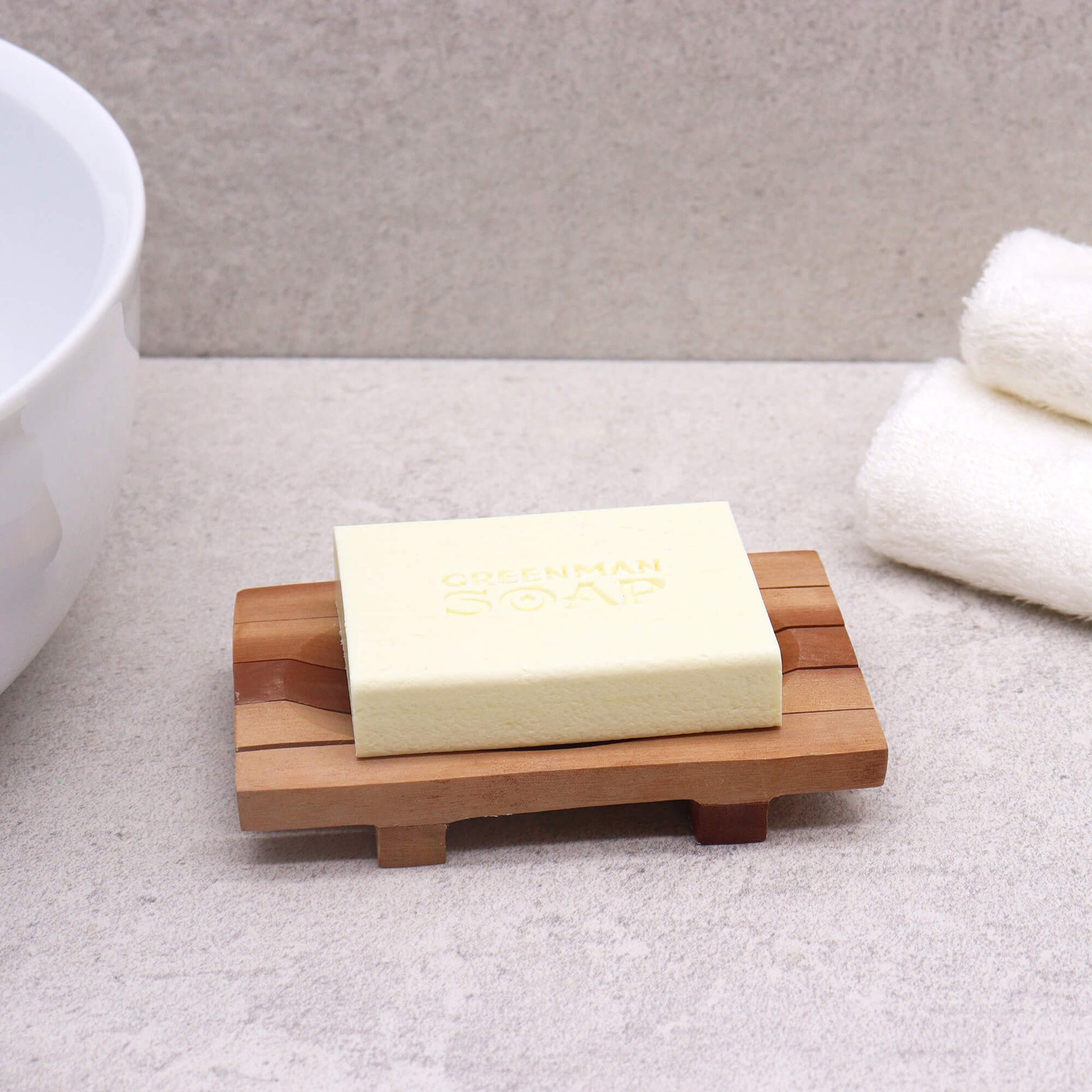 Wooden dish for soap with a bar of soap on a bathroom counter - Kraas