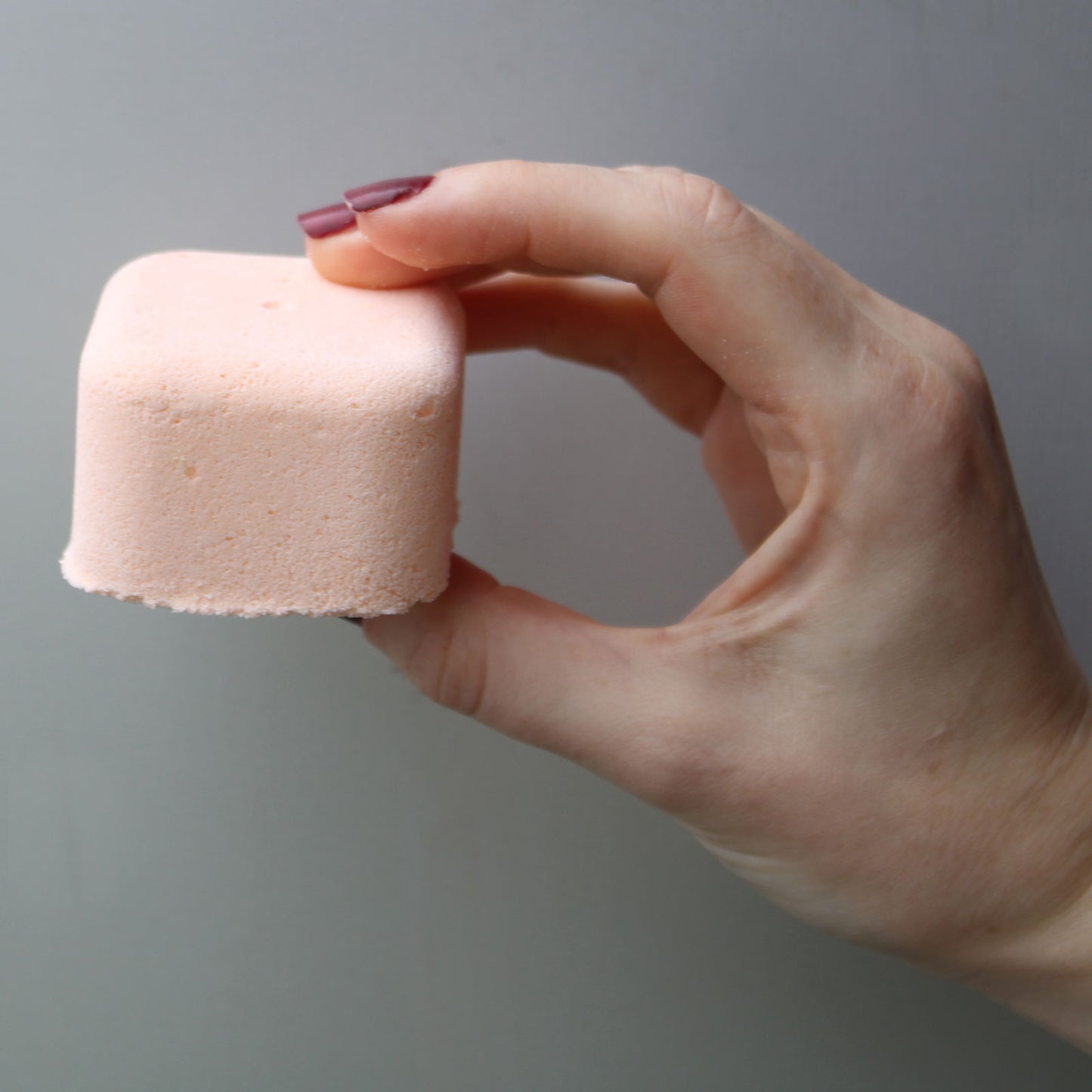 Female hand holding revitalise shower steamer - Kraas